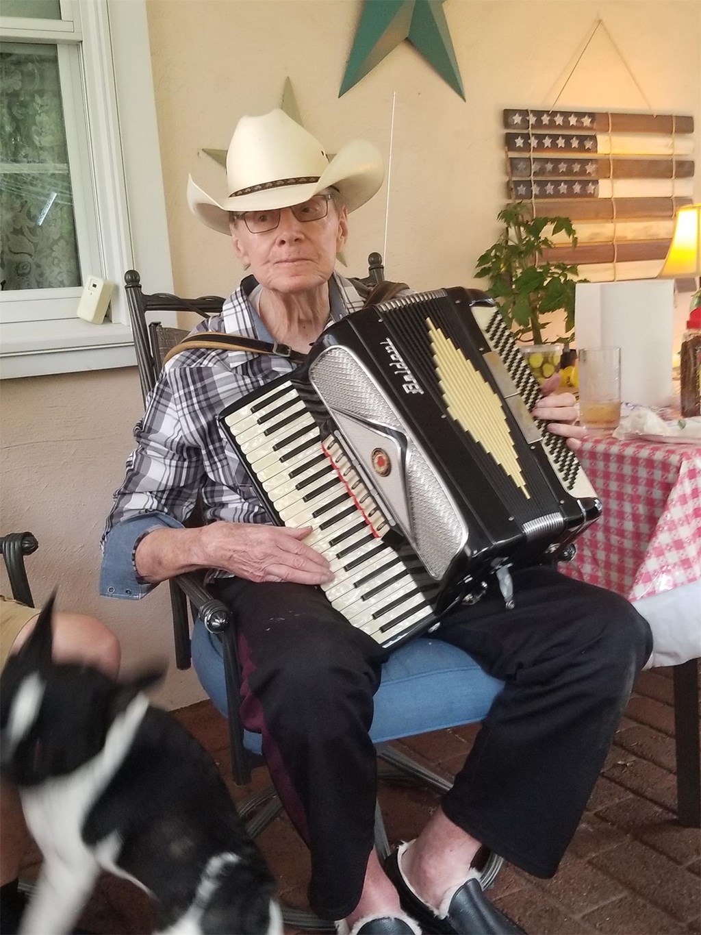 A photo of John Stanky sitting in his rocking chair with his accordion. 