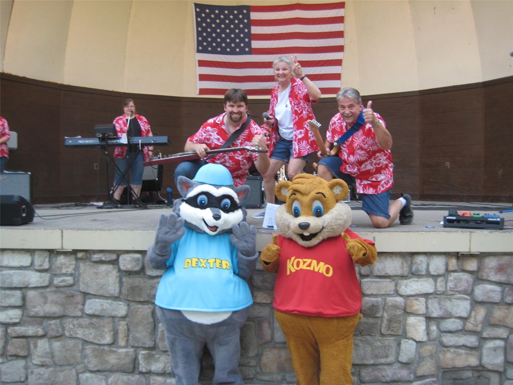 Members of Lucky Afternoon pose for a photo with park mascots Kozmo and Dexter at the Hawaiian Bandshell stage. 